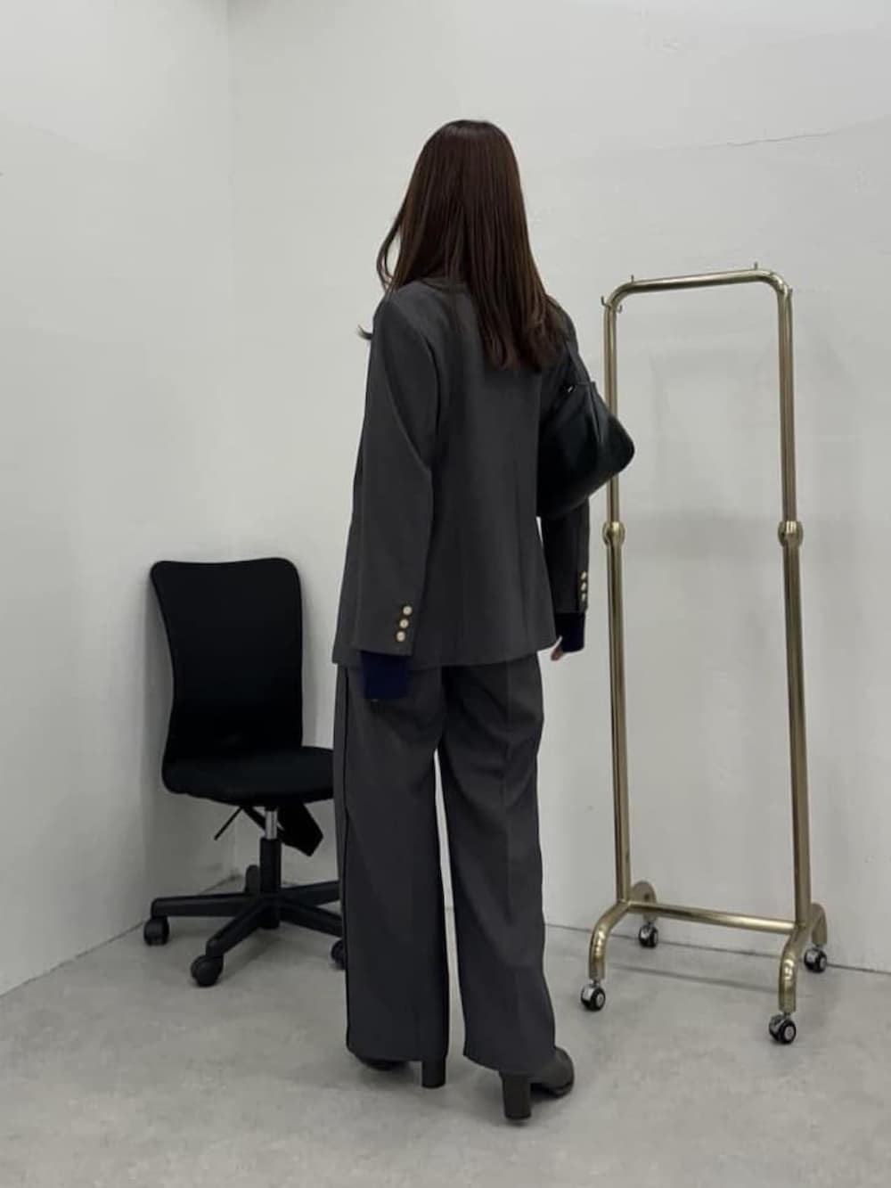 グレー系のスラックス、ブラウン系のブーツ、ブルー系のニット/セーターを着用したレディースの冬コーディネートの2枚目の写真