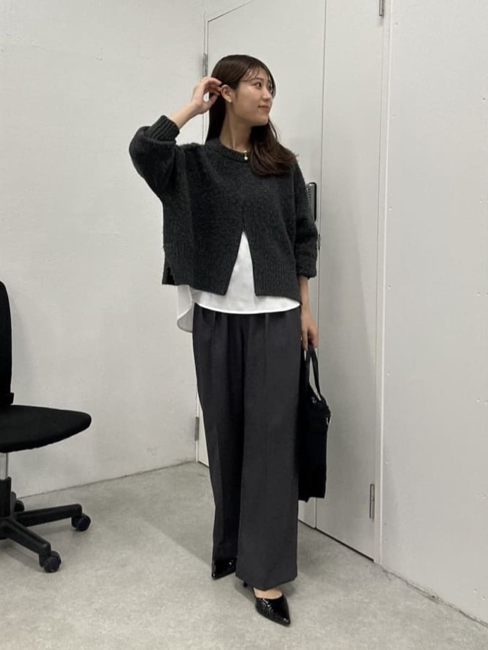 グレー系のニット/セーター、ホワイト系のシャツ/ブラウス、グレー系のスラックスを着用したレディースの冬コーディネートの2枚目の写真