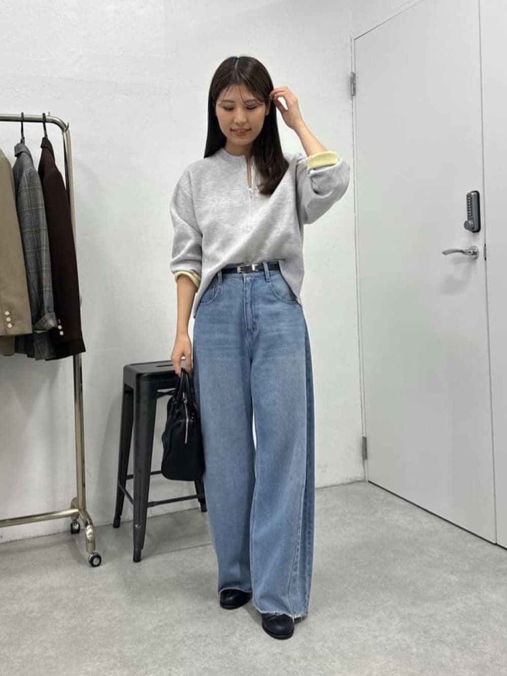 ブルー系のデニムパンツ、グレー系のニット/セーター、ブラック系のボストンバッグを着用したレディースの冬コーディネートの2枚目の写真