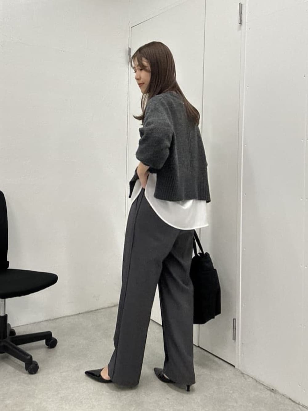 グレー系のニット/セーター、ホワイト系のシャツ/ブラウス、グレー系のスラックスを着用したレディースの冬コーディネートの3枚目の写真