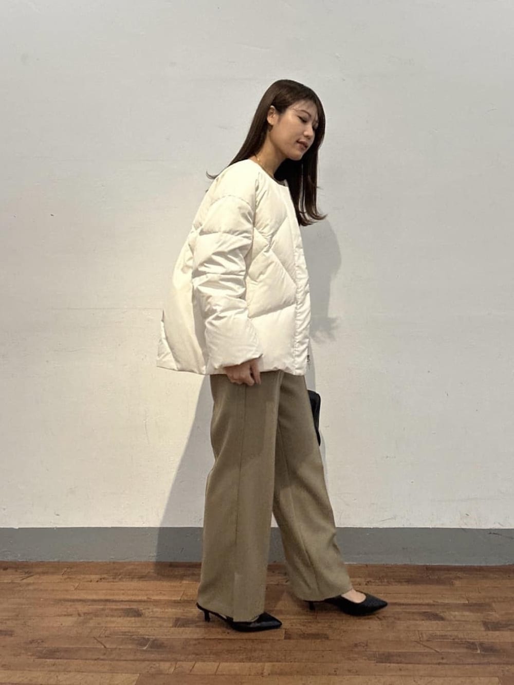 ホワイト系のダウンジャケット/コート、ブラック系のニット/セーター、ベージュ系のスラックスを着用したレディースの冬コーディネートの2枚目の写真