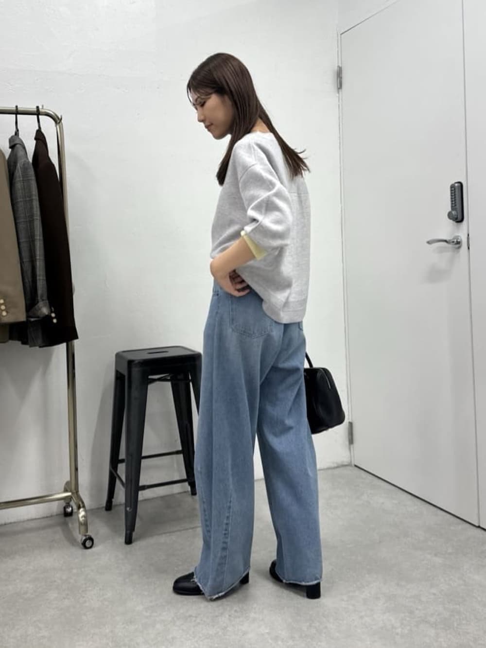 ブルー系のデニムパンツ、グレー系のニット/セーター、ブラック系のボストンバッグを着用したレディースの冬コーディネートの3枚目の写真