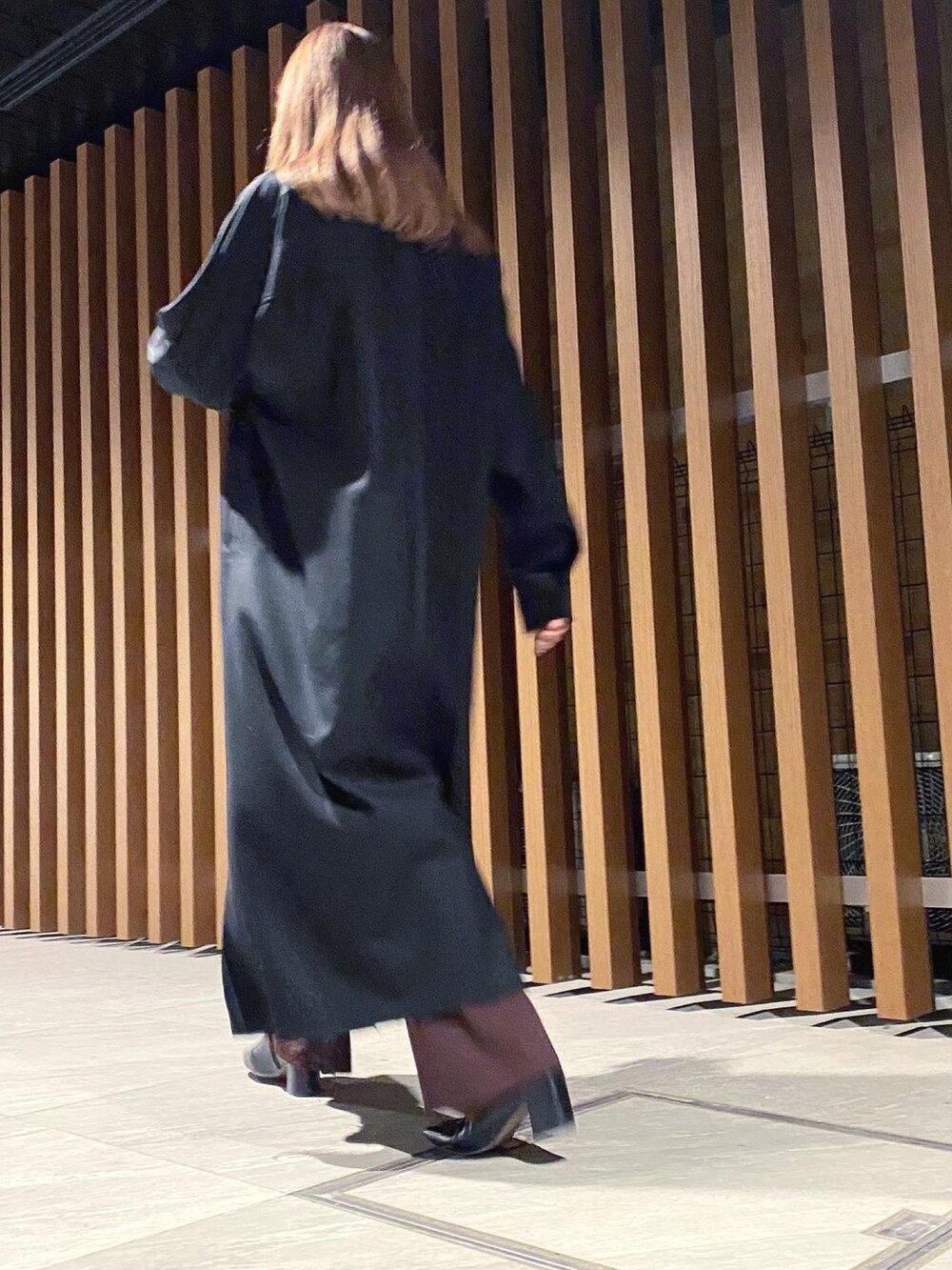 ブラック系のワンピース、ブラウン系のパンツを着用したレディースの秋コーディネートの2枚目の写真