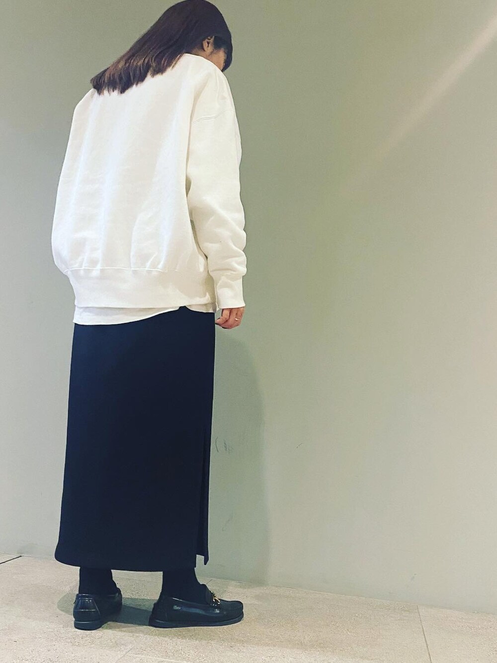 ホワイト系のスウェット、ブラック系のスカート、ブラック系のローファーを着用したレディースの秋コーディネートの2枚目の写真