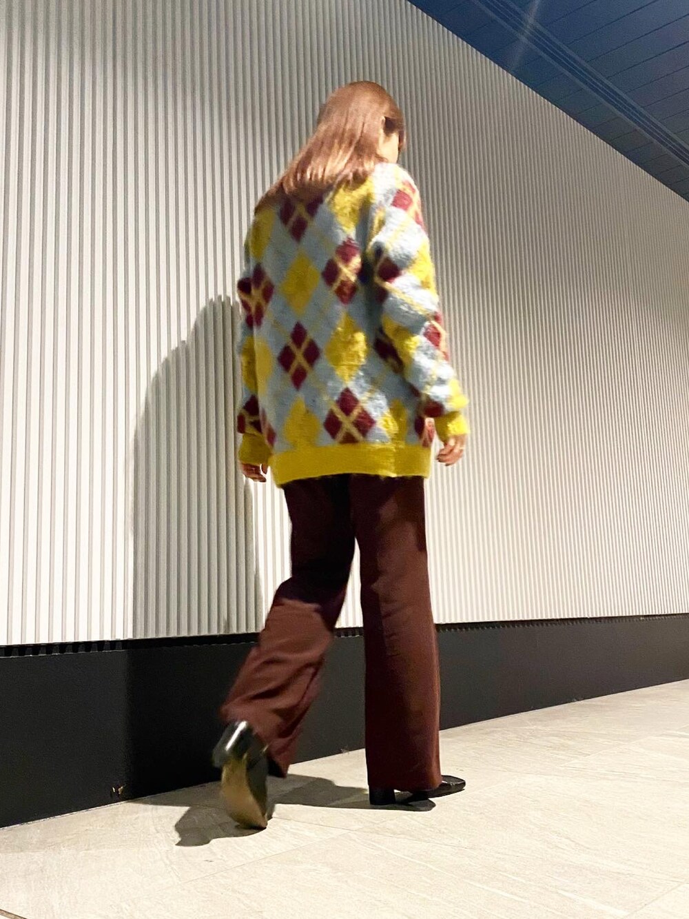 ブラウン系のパンツ、イエロー系のカーディガン/ボレロ、シルバー系のネックレスを着用したレディースの秋コーディネートの2枚目の写真