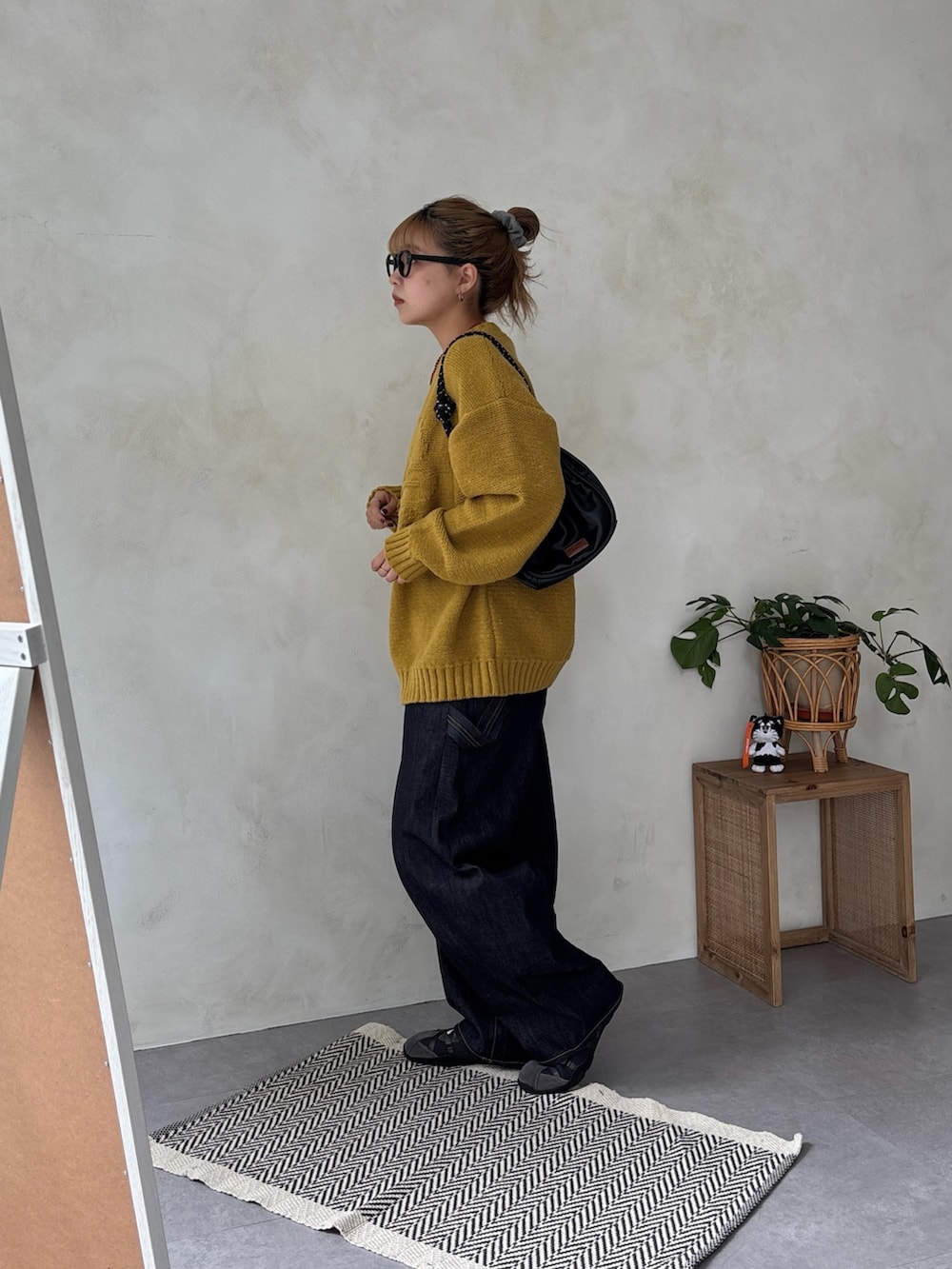 イエロー系のニット/セーター、ブルー系のデニムパンツを着用したレディースの冬コーディネートの2枚目の写真