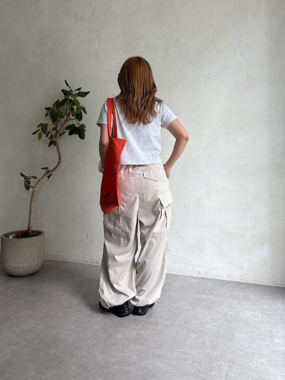 ホワイト系のカーゴパンツ、グレー系のTシャツ/カットソー、オレンジ系のトートバッグを着用したレディースの夏コーディネートの2枚目の写真
