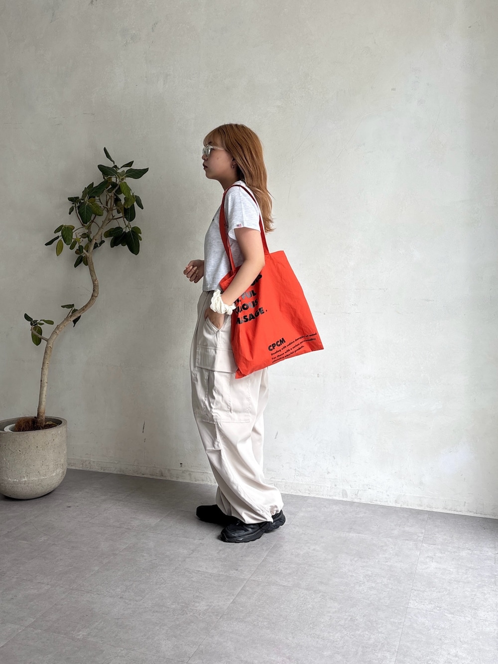 ホワイト系のカーゴパンツ、グレー系のTシャツ/カットソー、オレンジ系のトートバッグを着用したレディースの夏コーディネートの3枚目の写真