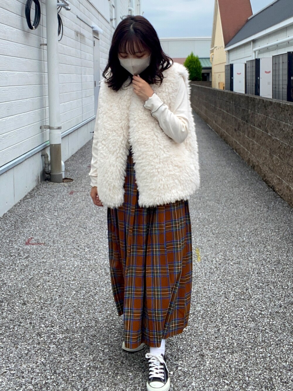 ホワイト系のベスト、ホワイト系のTシャツ/カットソー、イエロー系のスカートを着用したレディースの秋コーディネートの2枚目の写真