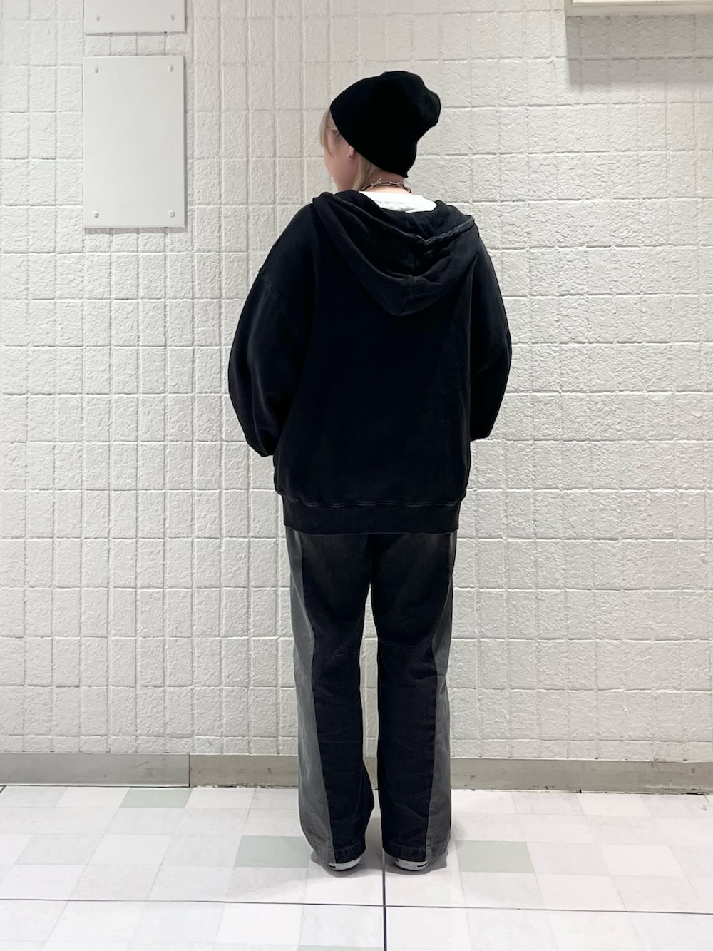 ブラック系のパーカー、ブラック系のデニムパンツ、ホワイト系のベルトを着用したレディースの秋コーディネートの3枚目の写真