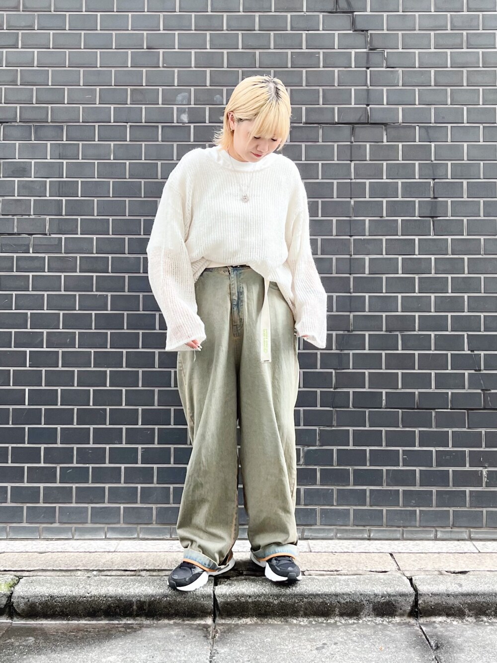 ホワイト系のニット/セーター、ホワイト系のTシャツ/カットソー、ブルー系のデニムパンツを着用したレディースの秋コーディネートの4枚目の写真