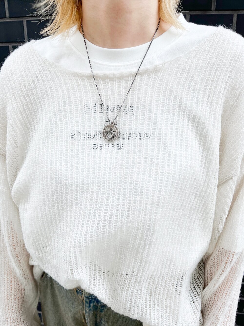 ホワイト系のニット/セーター、ホワイト系のTシャツ/カットソー、ブルー系のデニムパンツを着用したレディースの秋コーディネートの3枚目の写真