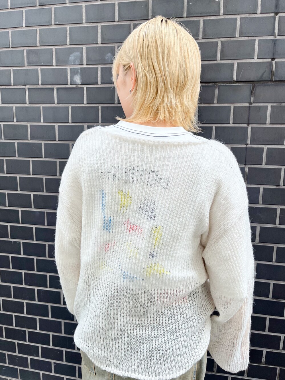 ホワイト系のニット/セーター、ホワイト系のTシャツ/カットソー、ブルー系のデニムパンツを着用したレディースの秋コーディネートの2枚目の写真