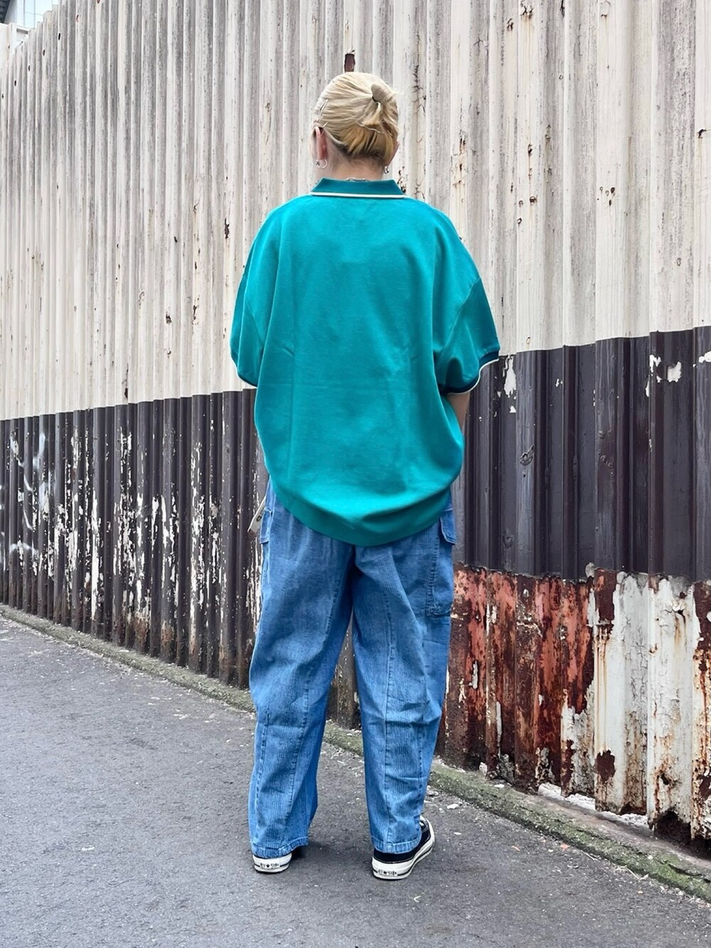 グリーン系のポロシャツ、ブルー系のデニムパンツ、ホワイト系のベルトを着用したレディースの春コーディネートの2枚目の写真