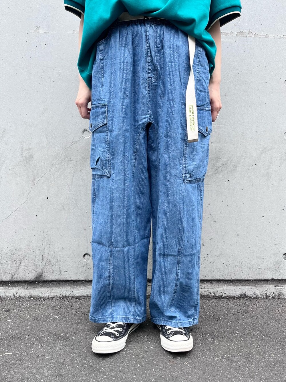 グリーン系のポロシャツ、ブルー系のデニムパンツ、ホワイト系のベルトを着用したレディースの春コーディネートの3枚目の写真