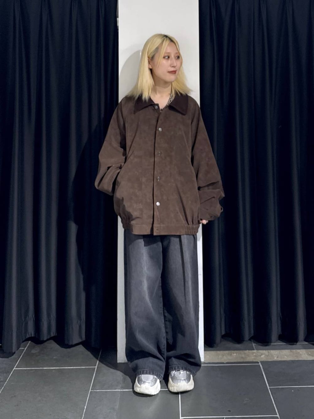 ブラック系のデニムパンツ、シルバー系のスニーカー、ブラウン系のブルゾンを着用したレディースの秋コーディネートの2枚目の写真