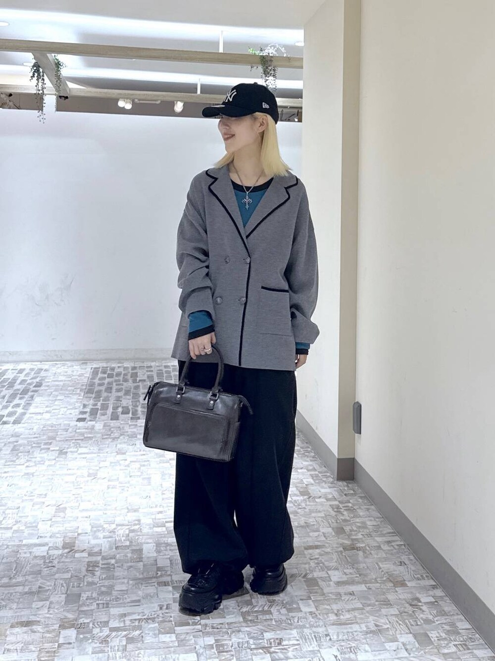 ブラック系のスニーカー、ブラック系のデニムパンツ、グレー系のテーラードジャケットを着用したレディースの冬コーディネートの3枚目の写真