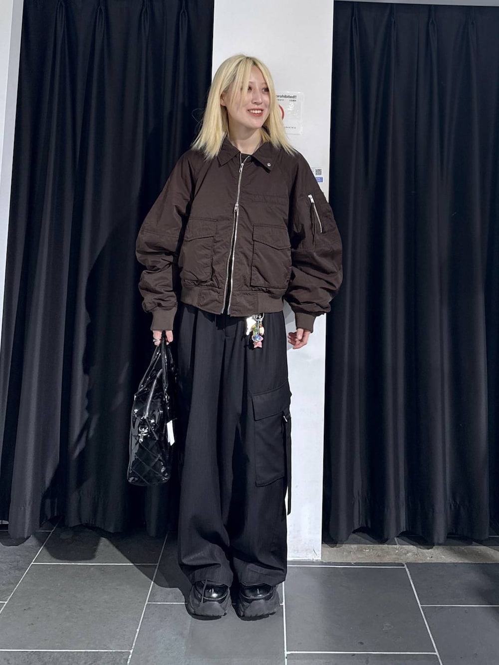 ブラック系のブーツ、ブラック系のスラックス、ブラウン系のブルゾンを着用したレディースの秋コーディネートの3枚目の写真