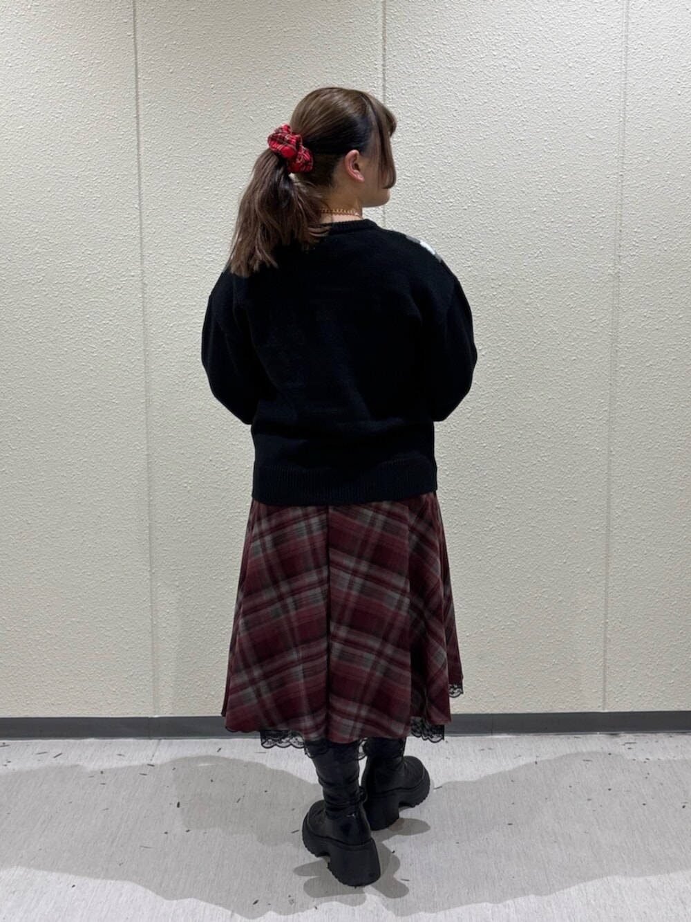 ブラック系のブーツ、レッド系のスカート、ブラック系のニット/セーターを着用したレディースの冬コーディネートの3枚目の写真