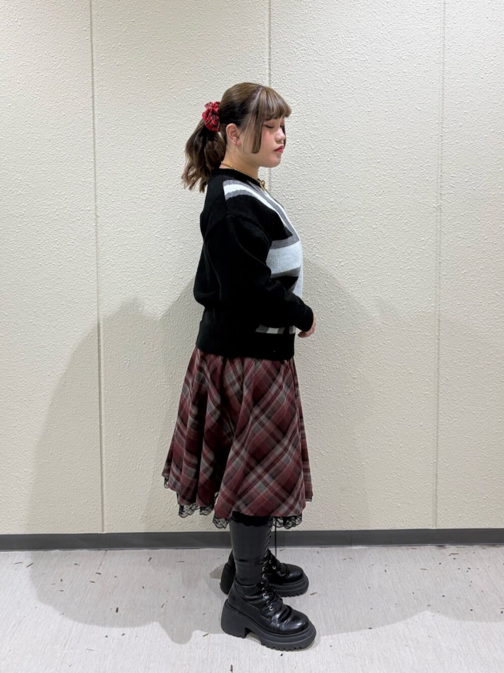 ブラック系のブーツ、レッド系のスカート、ブラック系のニット/セーターを着用したレディースの冬コーディネートの2枚目の写真