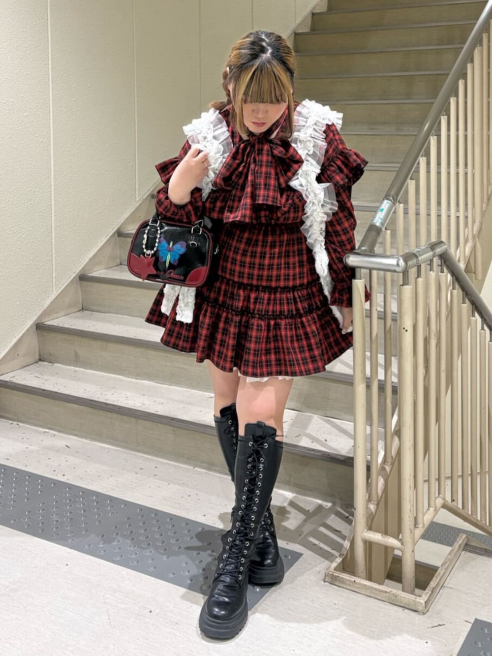 ブラック系のブーツ、レッド系のワンピース、ブラック系のボストンバッグを着用したレディースの冬コーディネートの2枚目の写真