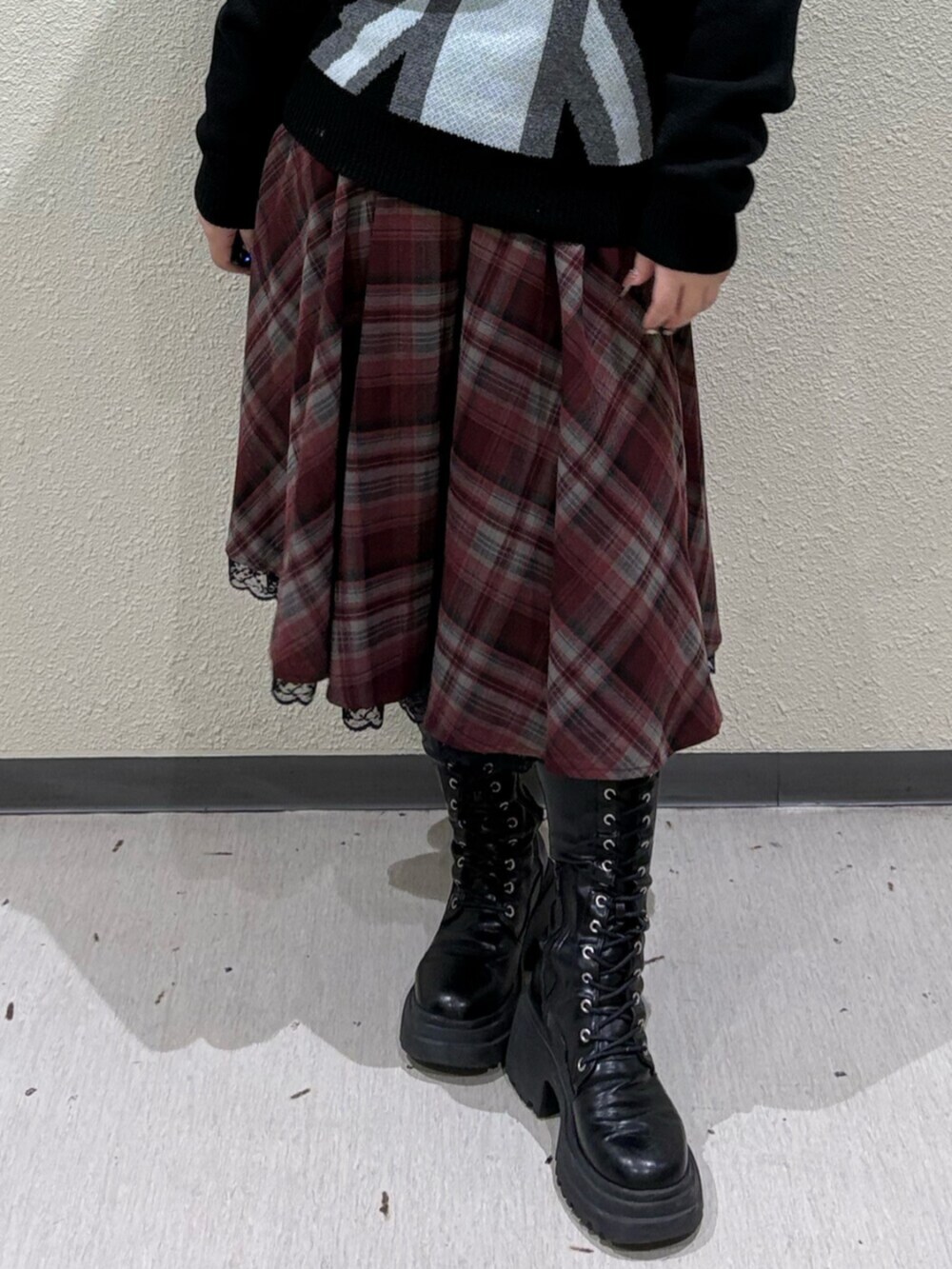 ブラック系のブーツ、レッド系のスカート、ブラック系のニット/セーターを着用したレディースの冬コーディネートの5枚目の写真