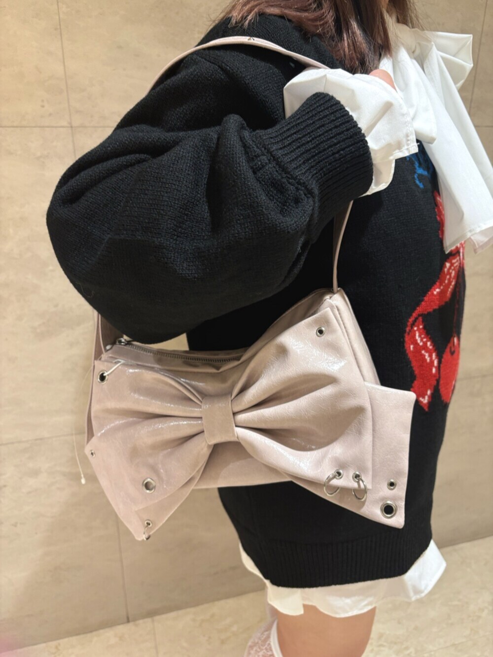 ブラック系のニット/セーター、ピンク系のショルダーバッグ、ブラウン系のブーツを着用したレディースの秋コーディネートの6枚目の写真