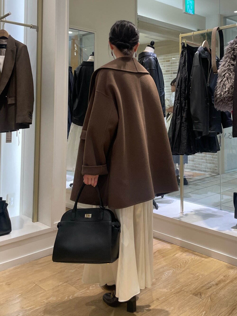 ブラウン系のその他アウター、ベージュ系のニット/セーター、ホワイト系のスカートを着用したレディースの秋コーディネートの3枚目の写真