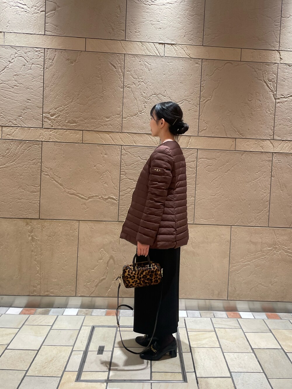 ブラウン系のダウンジャケット/コート、イエロー系のカーディガン/ボレロ、ブラック系のスカートを着用したレディースの秋コーディネートの2枚目の写真