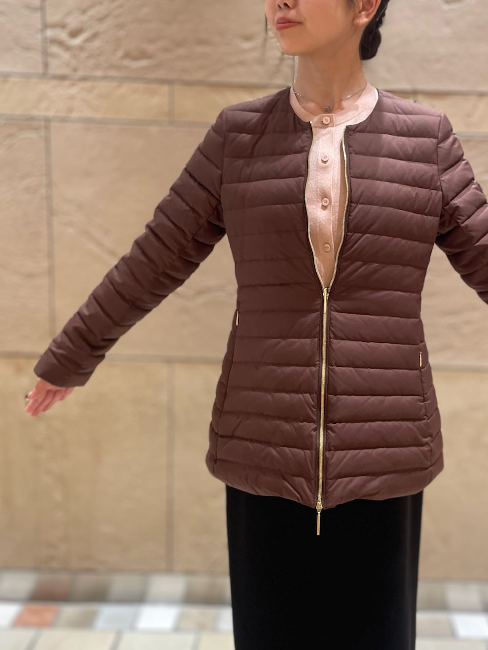 ブラウン系のダウンジャケット/コート、イエロー系のカーディガン/ボレロ、ブラック系のスカートを着用したレディースの秋コーディネートの8枚目の写真