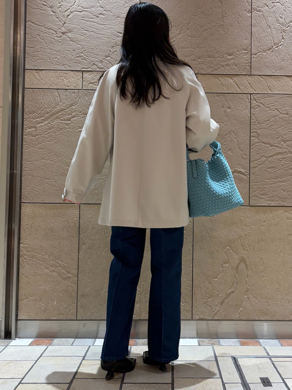ベージュ系のステンカラーコート、ブルー系のシャツ/ブラウス、ホワイト系のニット/セーターを着用したレディースの冬コーディネートの3枚目の写真