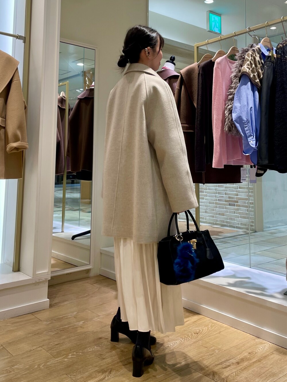 ベージュ系のステンカラーコート、ブルー系のシャツ/ブラウス、ブラック系のトートバッグを着用したレディースの秋コーディネートの5枚目の写真