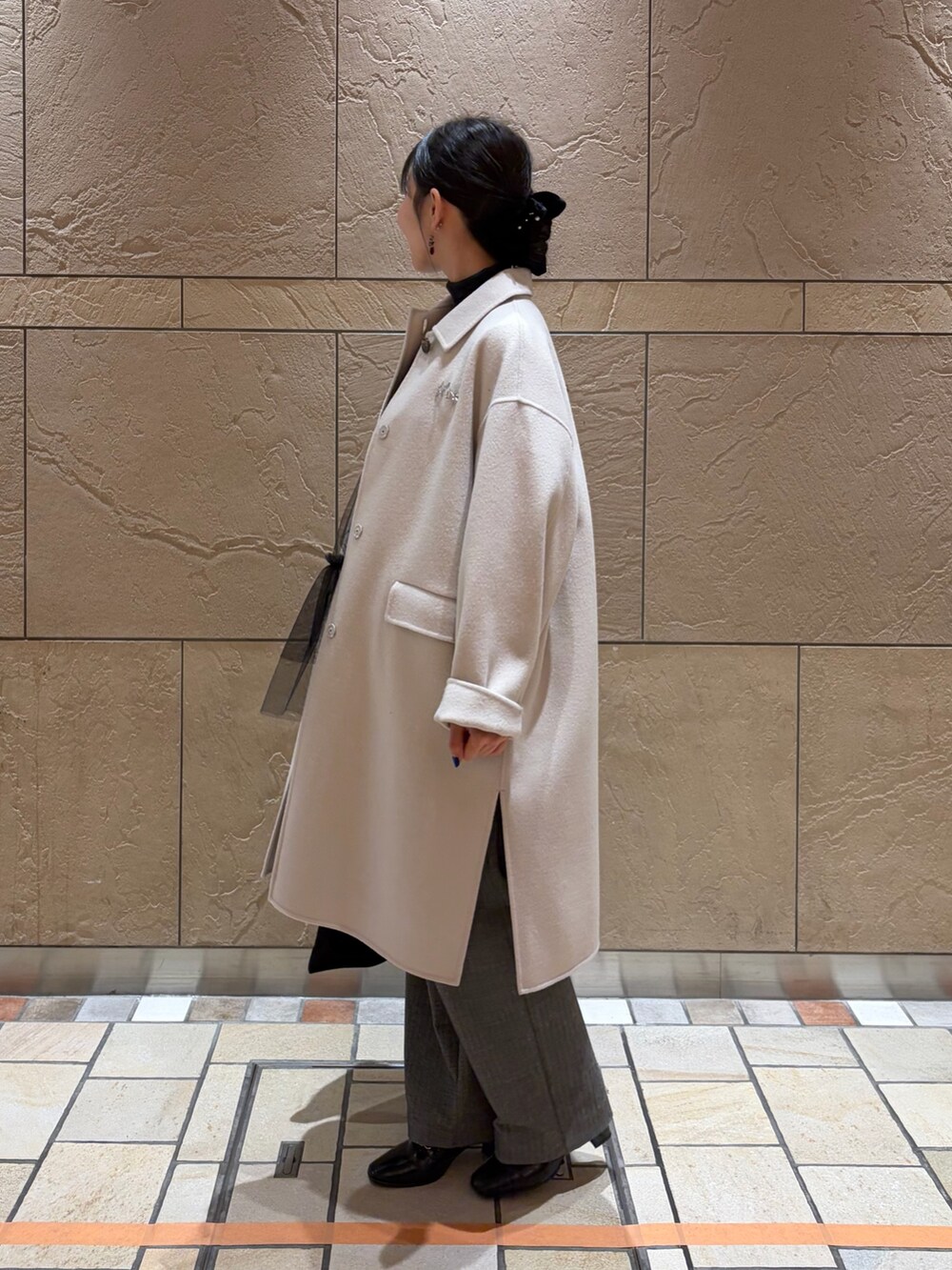 ベージュ系のステンカラーコート、グレー系のニット/セーター、ブラック系のキャミソールを着用したレディースの冬コーディネートの2枚目の写真