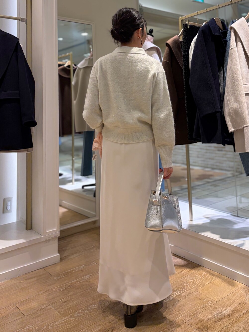 ホワイト系のニット/セーター、シルバー系のショルダーバッグ、ホワイト系のスカートを着用したレディースの秋コーディネートの3枚目の写真