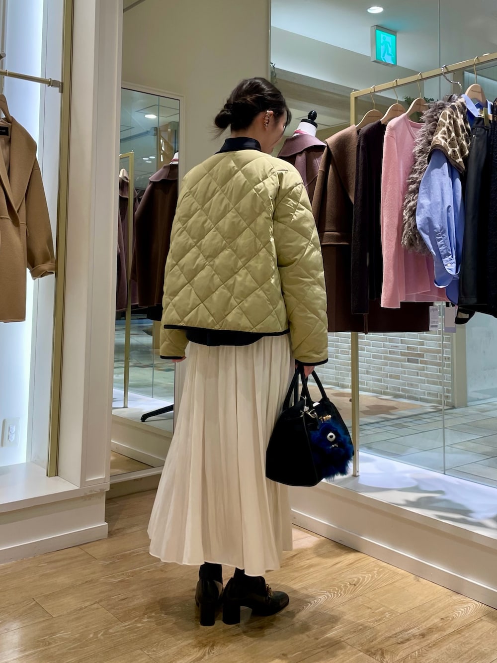 ブルー系のシャツ/ブラウス、ベージュ系のダウンジャケット/コート、ホワイト系のスカートを着用したレディースの秋コーディネートの5枚目の写真