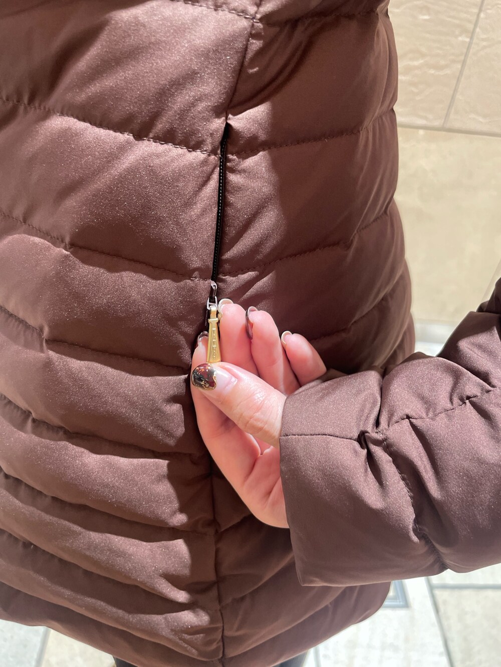 ブラウン系のダウンジャケット/コート、イエロー系のカーディガン/ボレロ、ブラック系のスカートを着用したレディースの秋コーディネートの7枚目の写真