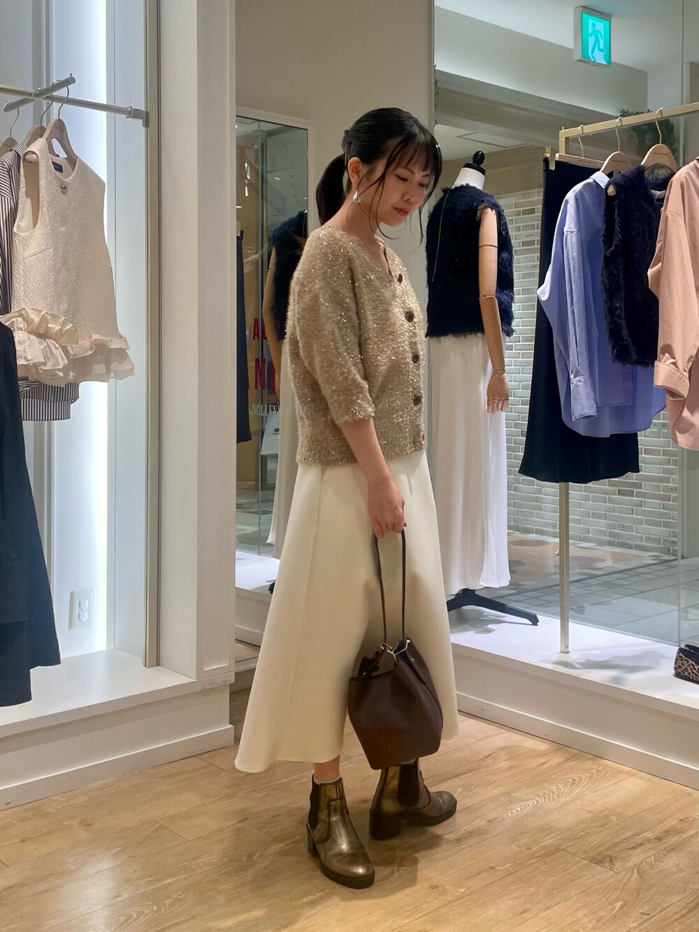 イエロー系のカーディガン/ボレロ、ホワイト系のスカート、ブラウン系のショルダーバッグを着用したレディースの秋コーディネートの6枚目の写真