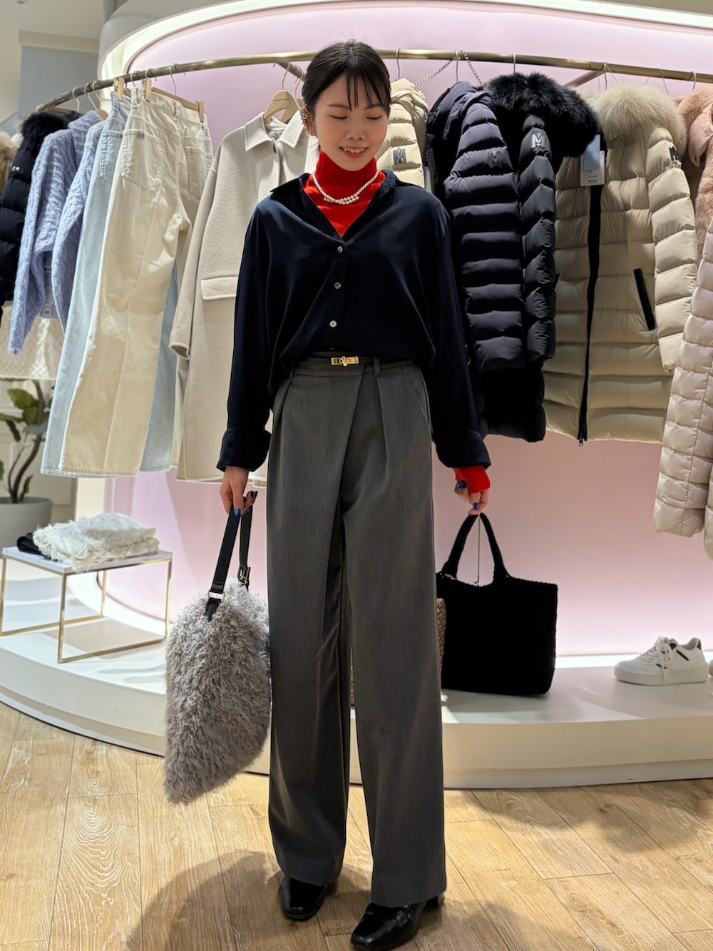 レッド系のニット/セーター、ホワイト系のシャツ/ブラウス、ベージュ系のショルダーバッグを着用したレディースの冬コーディネートの2枚目の写真