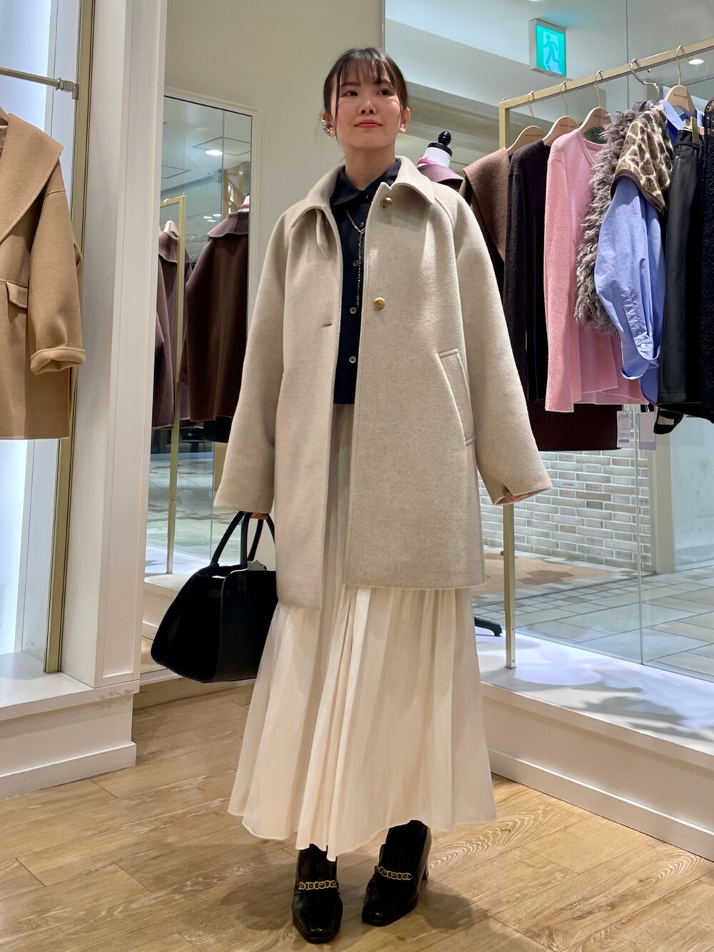 ベージュ系のステンカラーコート、ブルー系のシャツ/ブラウス、ブラック系のトートバッグを着用したレディースの秋コーディネートの7枚目の写真