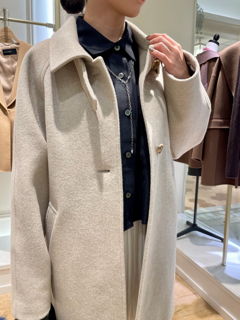 ベージュ系のステンカラーコート、ブルー系のシャツ/ブラウス、ブラック系のトートバッグを着用したレディースの秋コーディネートの10枚目の写真