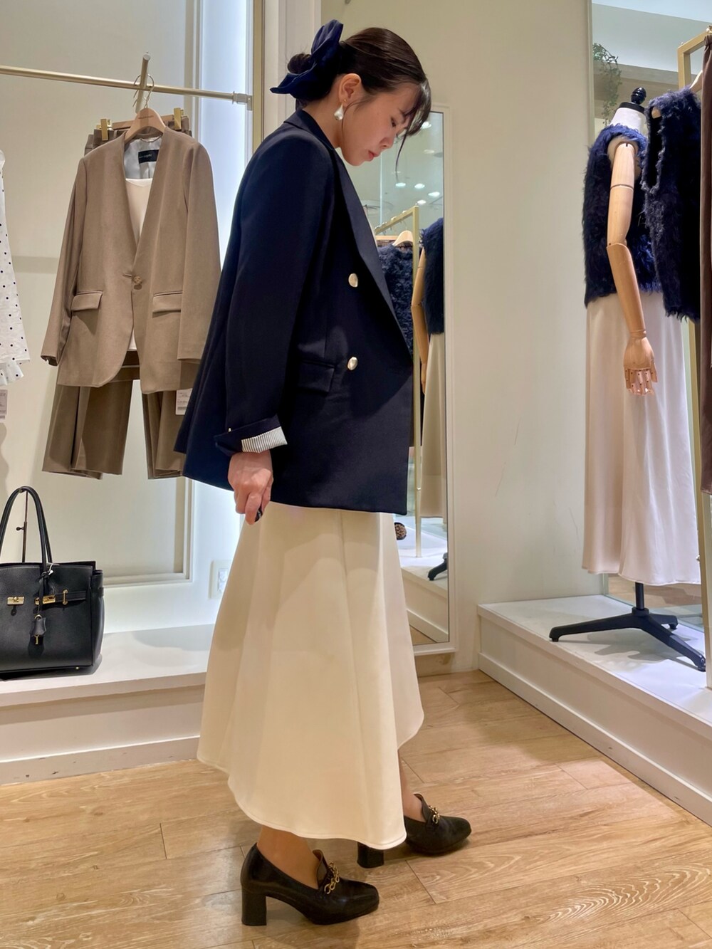 ブルー系のテーラードジャケット、ホワイト系のタンクトップ、ブラウン系のショルダーバッグを着用したレディースの秋コーディネートの4枚目の写真