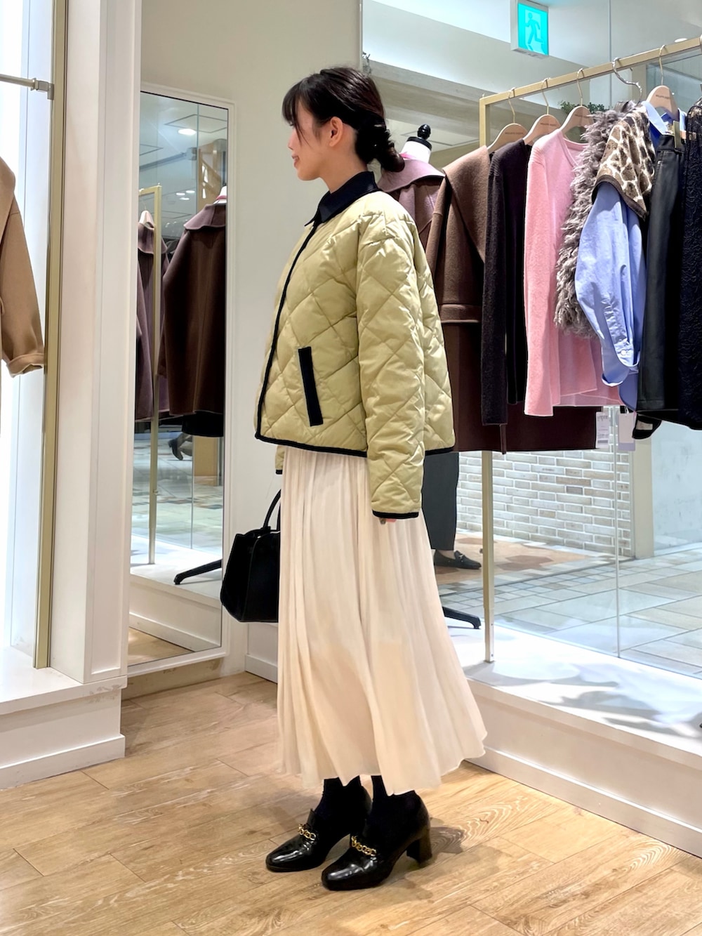 ブルー系のシャツ/ブラウス、ベージュ系のダウンジャケット/コート、ホワイト系のスカートを着用したレディースの秋コーディネートの2枚目の写真