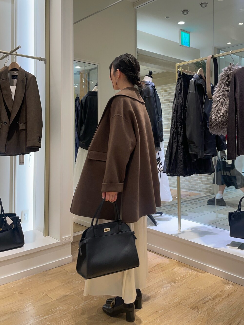 ブラウン系のその他アウター、ベージュ系のニット/セーター、ホワイト系のスカートを着用したレディースの秋コーディネートの2枚目の写真