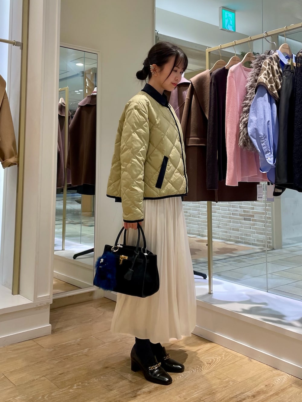 ブルー系のシャツ/ブラウス、ベージュ系のダウンジャケット/コート、ホワイト系のスカートを着用したレディースの秋コーディネートの7枚目の写真