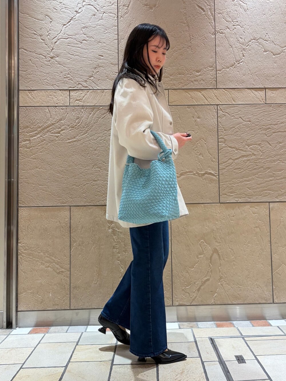 ベージュ系のステンカラーコート、ブルー系のシャツ/ブラウス、ホワイト系のニット/セーターを着用したレディースの冬コーディネートの4枚目の写真