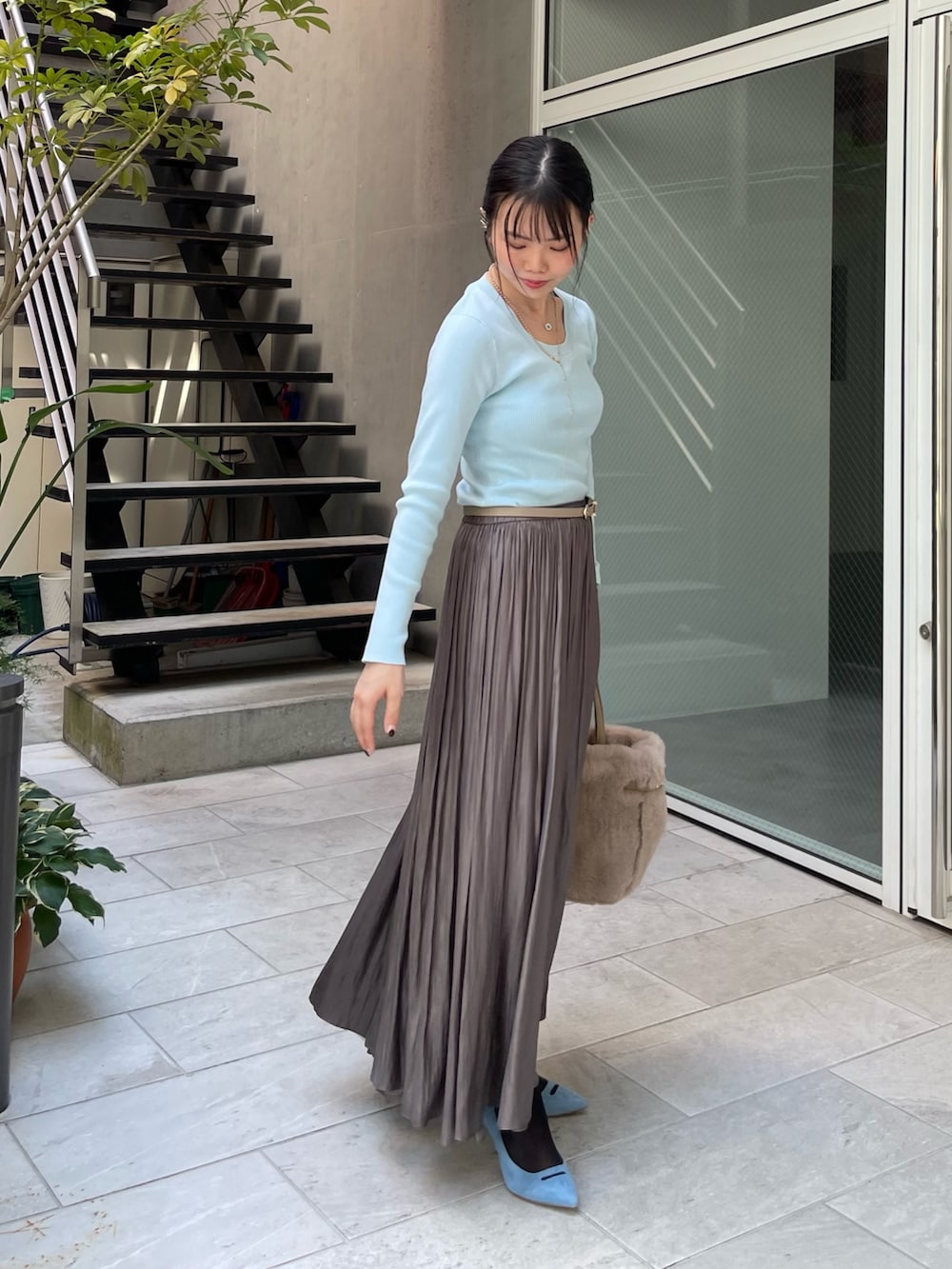 ブルー系のニット/セーター、グリーン系のスカート、ベージュ系のトートバッグを着用したレディースの秋コーディネートの3枚目の写真