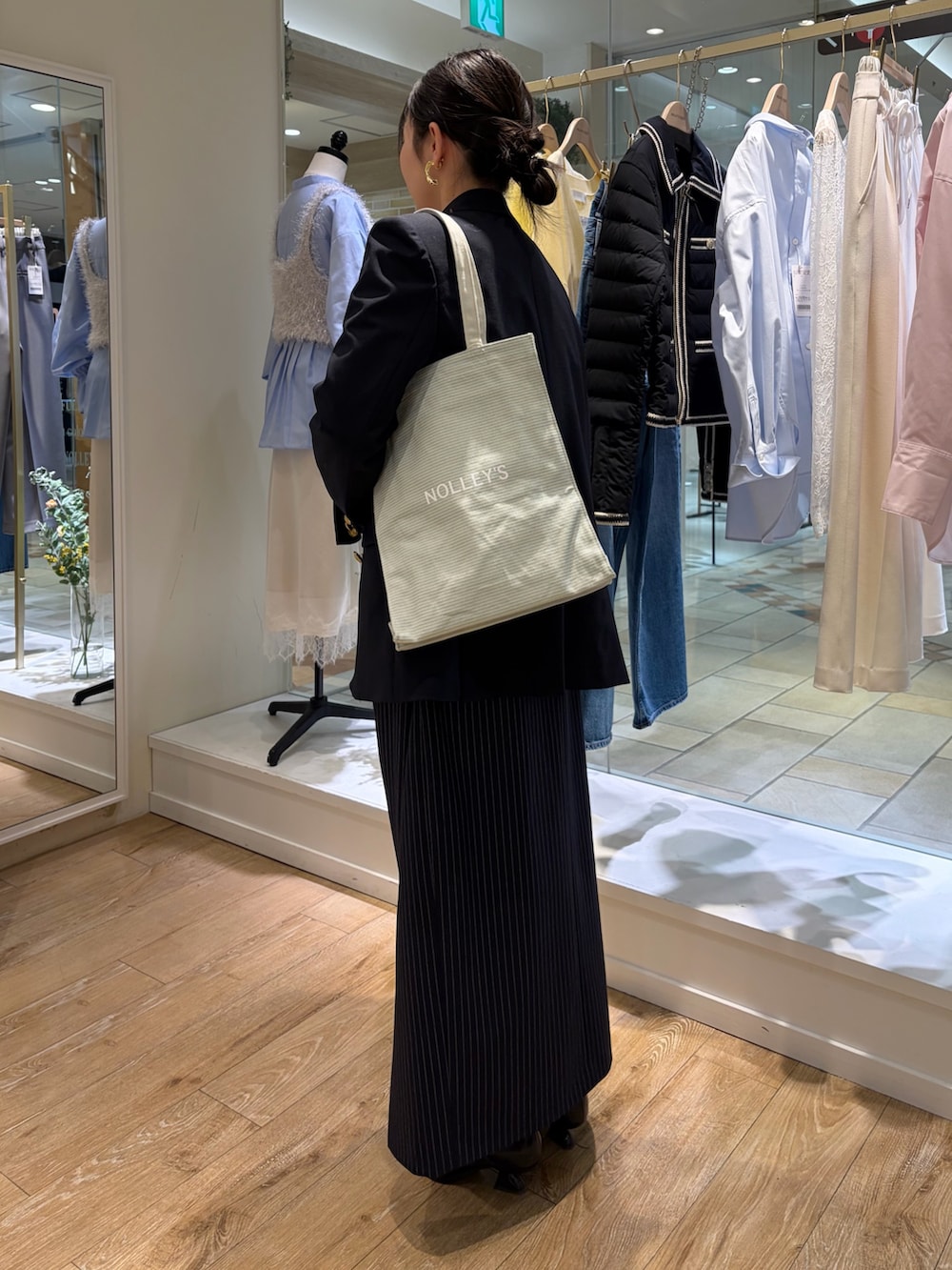 グレー系のトートバッグ、ブルー系のテーラードジャケット、ブルー系のキャミソールを着用したレディースの冬コーディネートの2枚目の写真