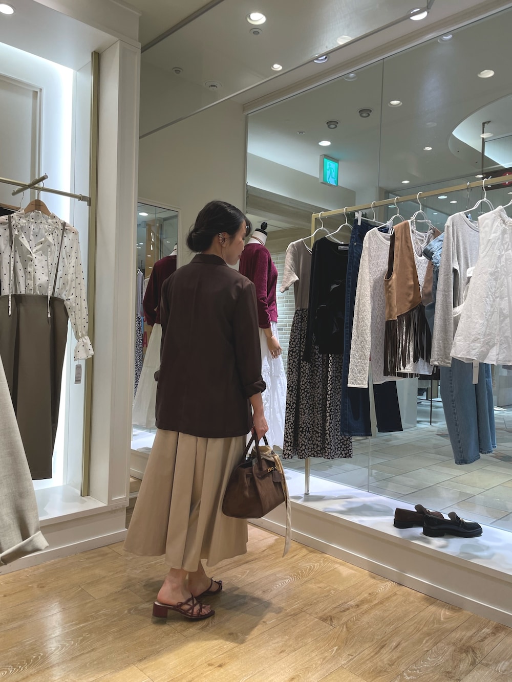 ブラウン系のテーラードジャケット、ブルー系のニット/セーター、ベージュ系のスカートを着用したレディースの秋コーディネートの3枚目の写真