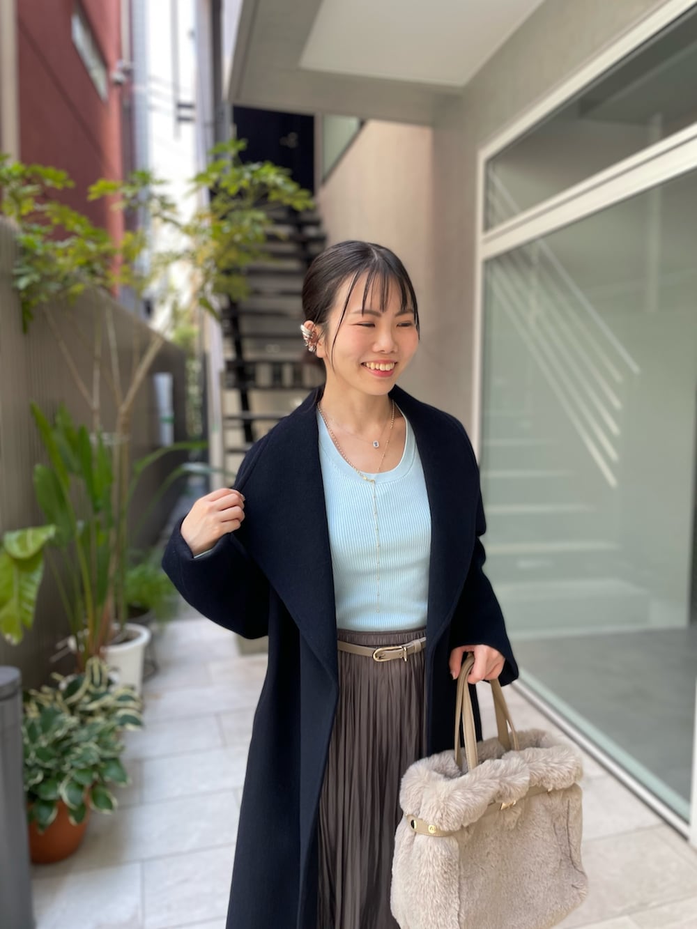 ブルー系のニット/セーター、ベージュ系のトートバッグ、グリーン系のスカートを着用したレディースの秋コーディネートの8枚目の写真