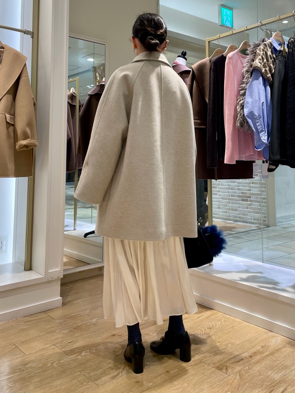 ベージュ系のステンカラーコート、ブルー系のシャツ/ブラウス、ブラック系のトートバッグを着用したレディースの秋コーディネートの4枚目の写真